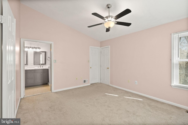 unfurnished bedroom with visible vents, connected bathroom, baseboards, lofted ceiling, and light carpet