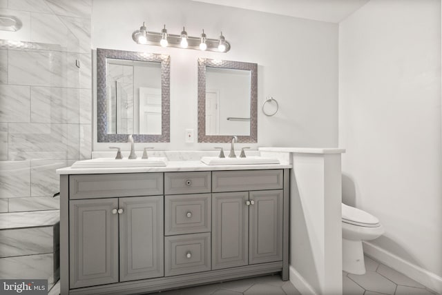 full bathroom with a sink, baseboards, toilet, and double vanity