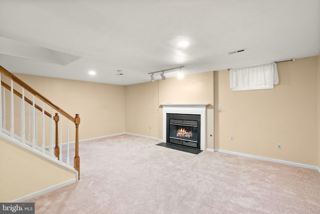 unfurnished living room featuring visible vents, baseboards, stairway, a fireplace with flush hearth, and carpet flooring