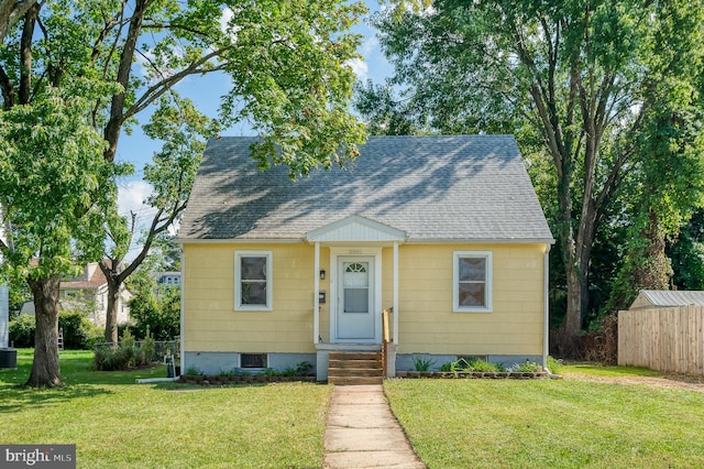 bungalow-style house featuring a front lawn and roof with shingles