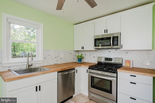 kitchen featuring tasteful backsplash, butcher block countertops, stainless steel appliances, and a sink