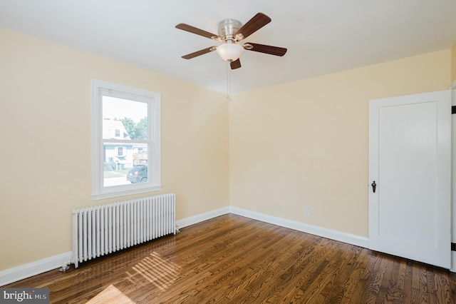 spare room with baseboards, dark wood-style flooring, and radiator heating unit