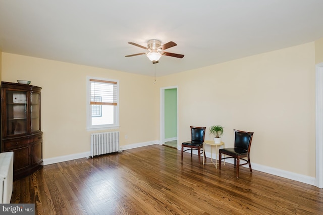 living area with a ceiling fan, radiator heating unit, baseboards, and wood finished floors