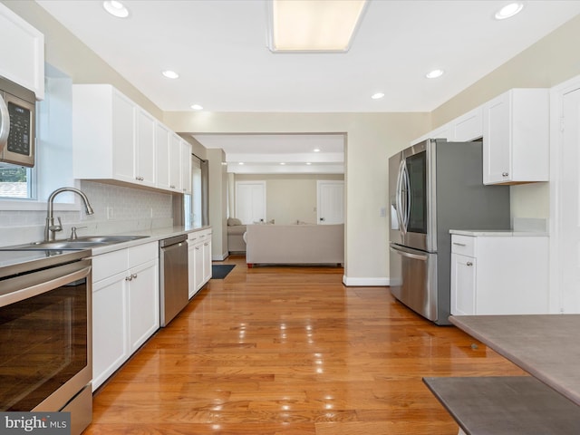 kitchen with stainless steel appliances, decorative backsplash, light countertops, and white cabinetry