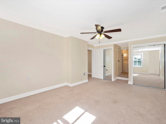 unfurnished bedroom with multiple closets, visible vents, baseboards, and light carpet