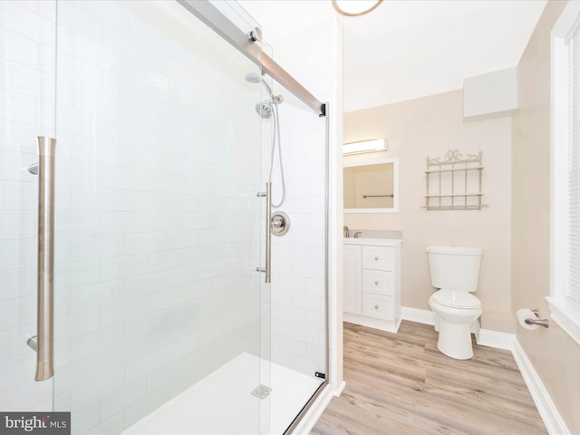 full bath with a shower stall, baseboards, toilet, wood finished floors, and vanity