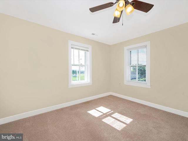 carpeted empty room with a ceiling fan, visible vents, and baseboards