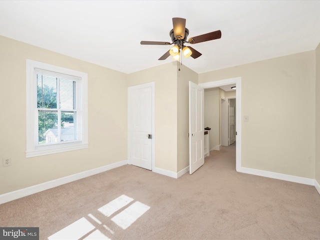 unfurnished bedroom with baseboards, light colored carpet, and a ceiling fan