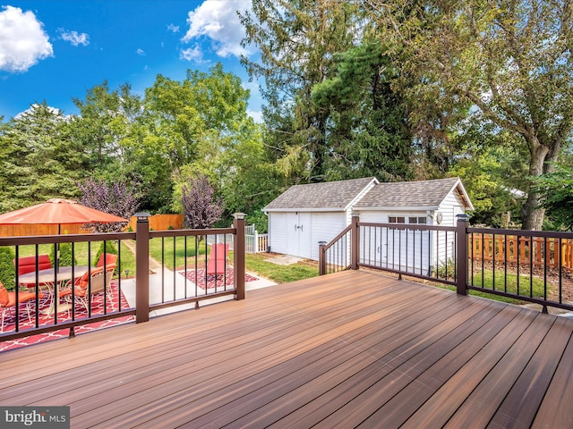 wooden deck featuring an outbuilding and fence