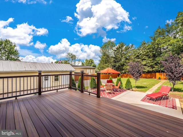 wooden terrace featuring a patio area, a lawn, outdoor dining area, and a fenced backyard