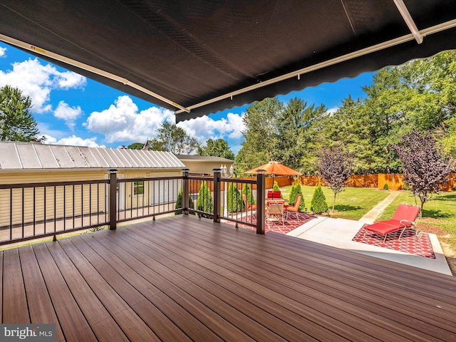 wooden deck with a patio, a lawn, and a fenced backyard