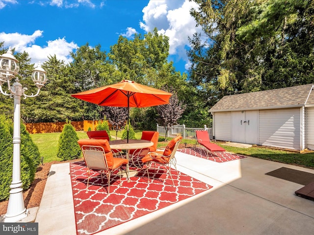 view of patio featuring outdoor dining space, an outdoor structure, and fence