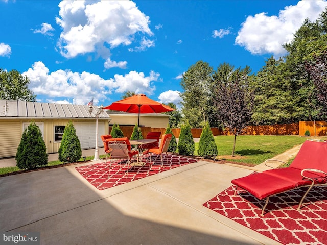 view of patio / terrace with an outbuilding, outdoor dining area, and fence