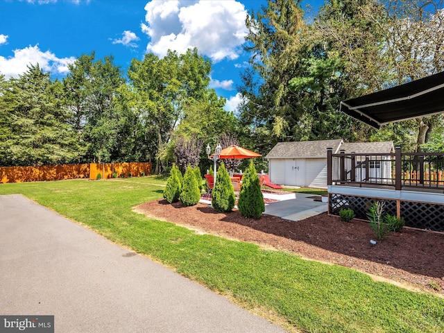 view of yard with a patio, an outdoor structure, a deck, and fence