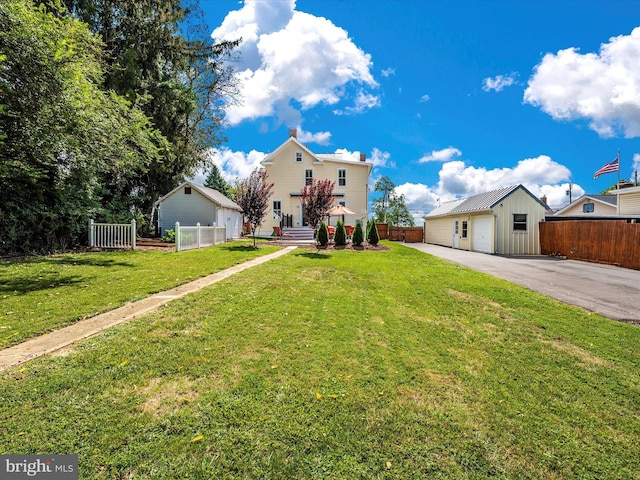 view of front of house featuring driveway, a front yard, and fence