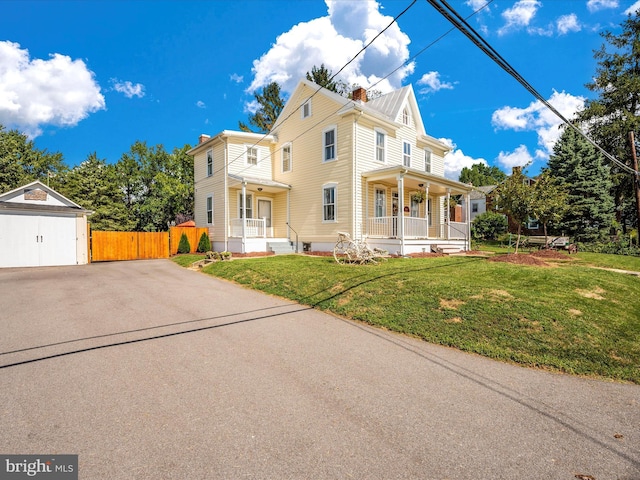 view of front of house with a front lawn, fence, covered porch, a chimney, and a garage