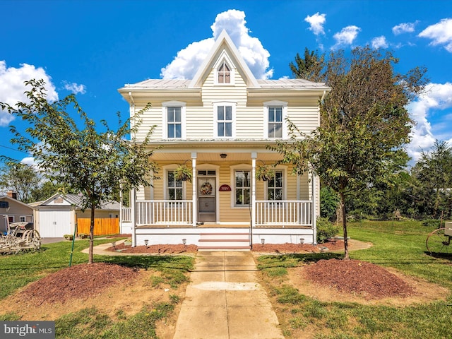 view of front of house featuring covered porch, metal roof, and a front yard