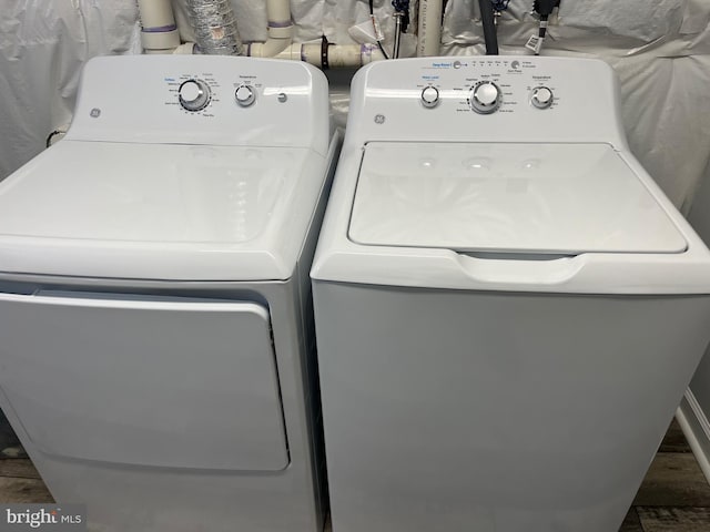 clothes washing area featuring laundry area, wood finished floors, and washer and clothes dryer