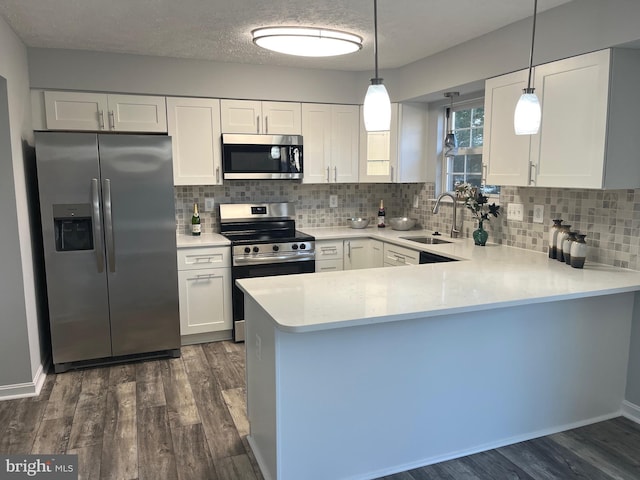 kitchen with a sink, appliances with stainless steel finishes, dark wood-style flooring, and light countertops