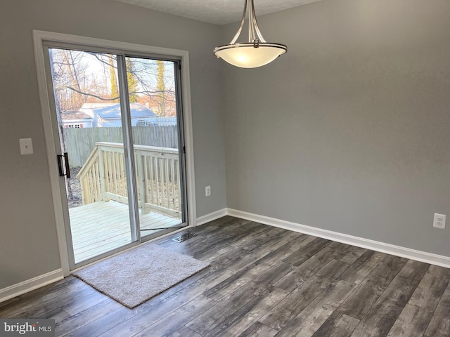 unfurnished dining area with dark wood-type flooring and baseboards