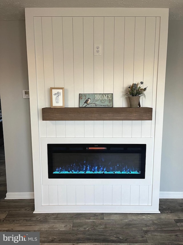 details featuring baseboards, a large fireplace, and wood finished floors