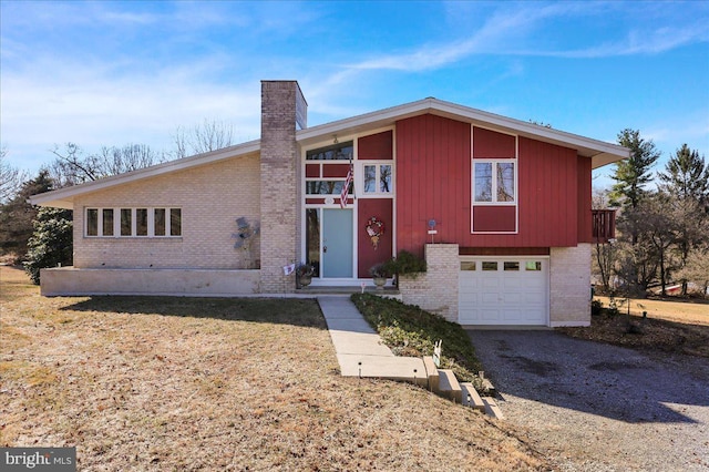 view of front facade with gravel driveway, an attached garage, brick siding, and a chimney