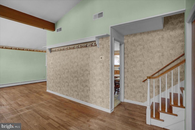 foyer entrance with visible vents, a baseboard radiator, lofted ceiling with beams, and wood finished floors