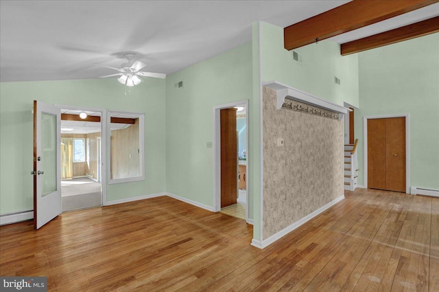 spare room with visible vents, stairway, lofted ceiling with beams, baseboard heating, and hardwood / wood-style flooring