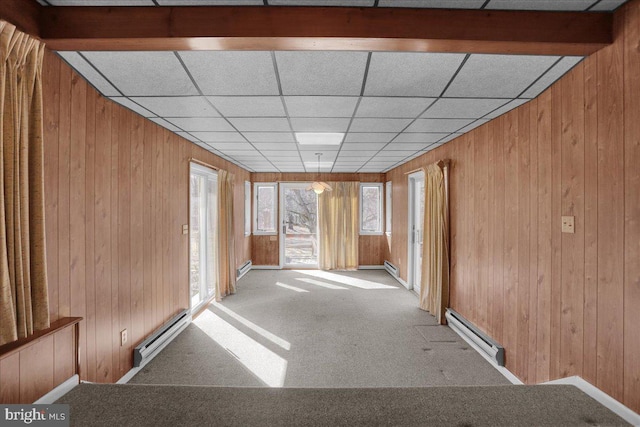 unfurnished room featuring a baseboard heating unit, wood walls, and carpet floors