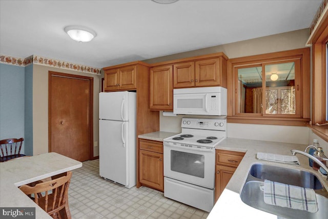 kitchen with light floors, white appliances, light countertops, and a sink