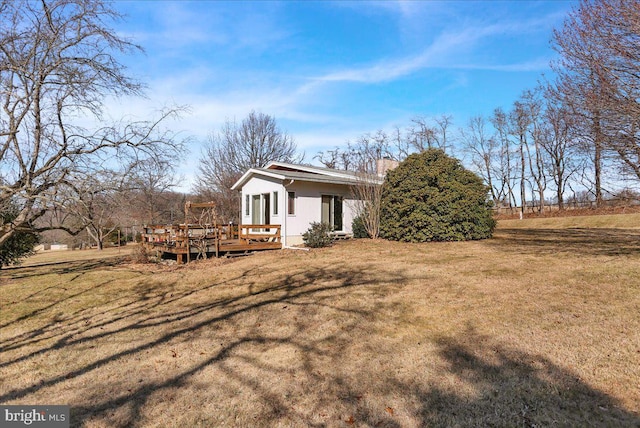 view of side of home with a deck and a yard