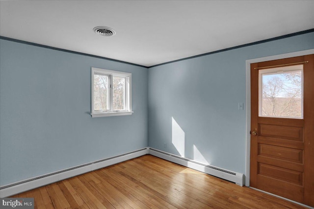 spare room featuring visible vents, a baseboard heating unit, crown molding, and wood-type flooring