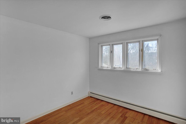 unfurnished room featuring light wood finished floors, baseboard heating, and visible vents