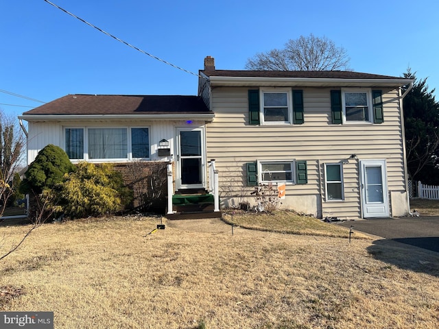 split level home featuring a front yard, a chimney, and entry steps