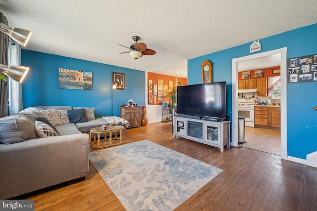 living area featuring hardwood / wood-style floors, a ceiling fan, and a textured ceiling
