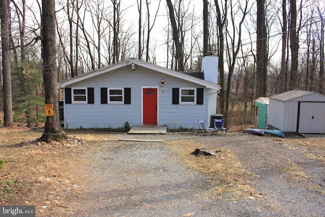 view of front facade featuring an outbuilding, a shed, cooling unit, and a chimney