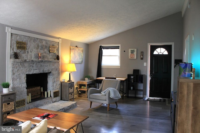 living room with a textured ceiling, a stone fireplace, wood finished floors, and vaulted ceiling