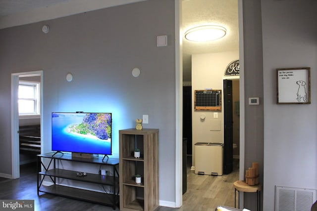 living area with visible vents, baseboards, and wood finished floors