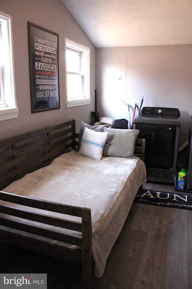 bedroom with lofted ceiling, a textured ceiling, washer / dryer, and wood finished floors