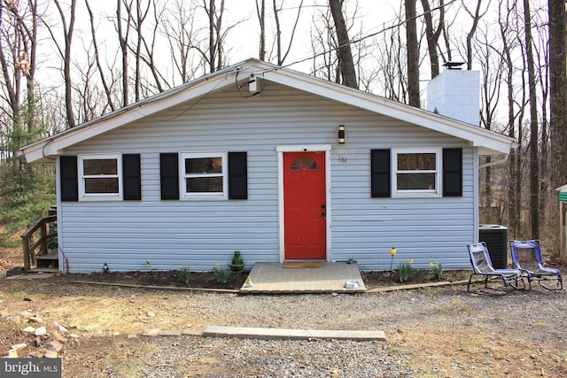 bungalow with central AC unit and a chimney