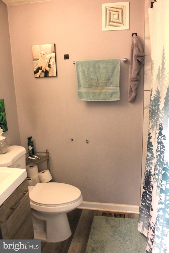 full bath featuring a shower with curtain, toilet, wood finished floors, baseboards, and vanity