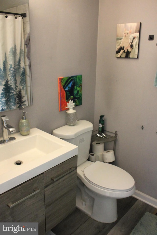 bathroom featuring curtained shower, baseboards, toilet, wood finished floors, and vanity