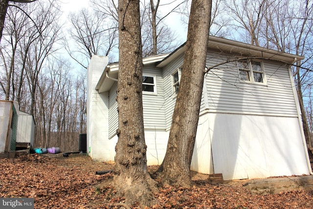 view of home's exterior with an outdoor structure, a storage unit, and a chimney