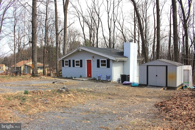 view of front facade with an outbuilding, cooling unit, a storage unit, and a chimney