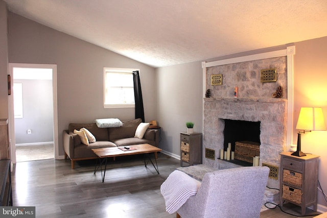 living room featuring a stone fireplace, lofted ceiling, wood finished floors, and baseboards