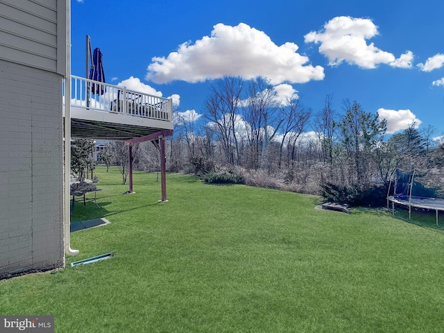 view of yard featuring a trampoline and a deck