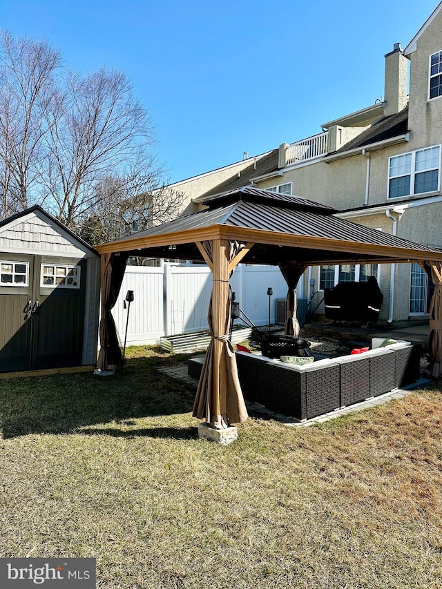 view of yard featuring a gazebo, an outbuilding, a storage unit, and fence