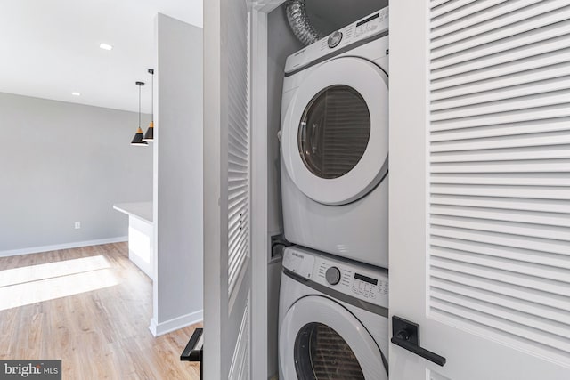 laundry area with baseboards, laundry area, recessed lighting, stacked washer and clothes dryer, and light wood-style floors