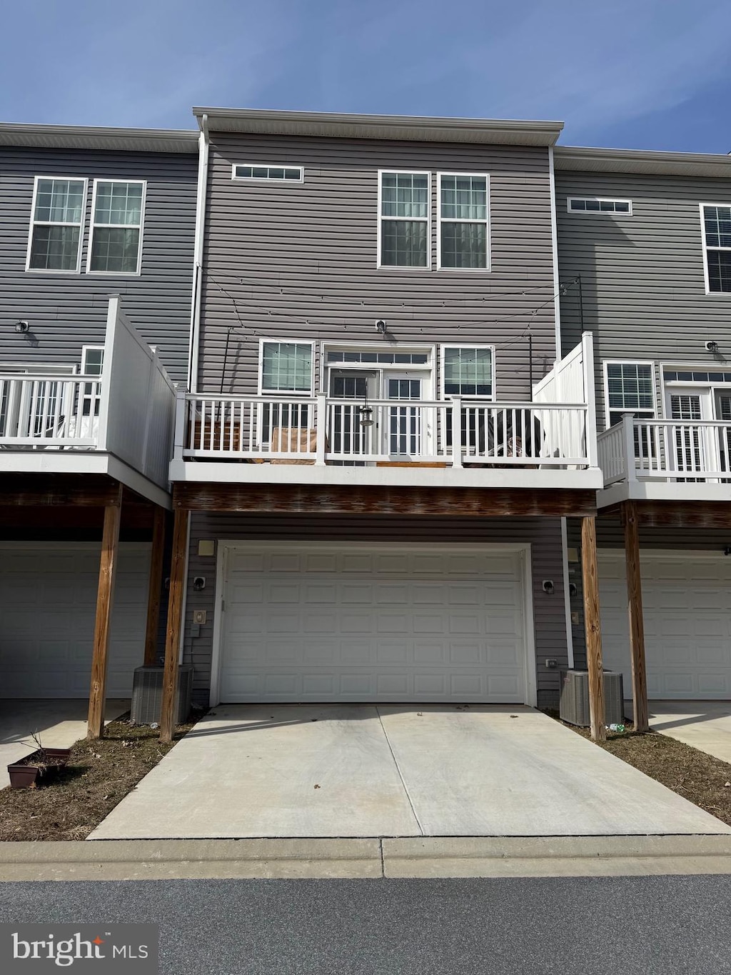 back of property with central AC unit, driveway, and an attached garage