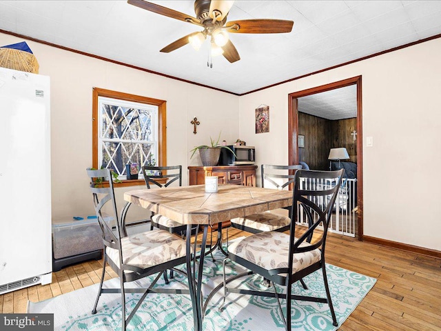 dining area featuring baseboards, ornamental molding, and light wood finished floors